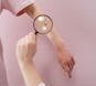 Close-up of a dermatologist examining skin with a magnifier on a pink background.